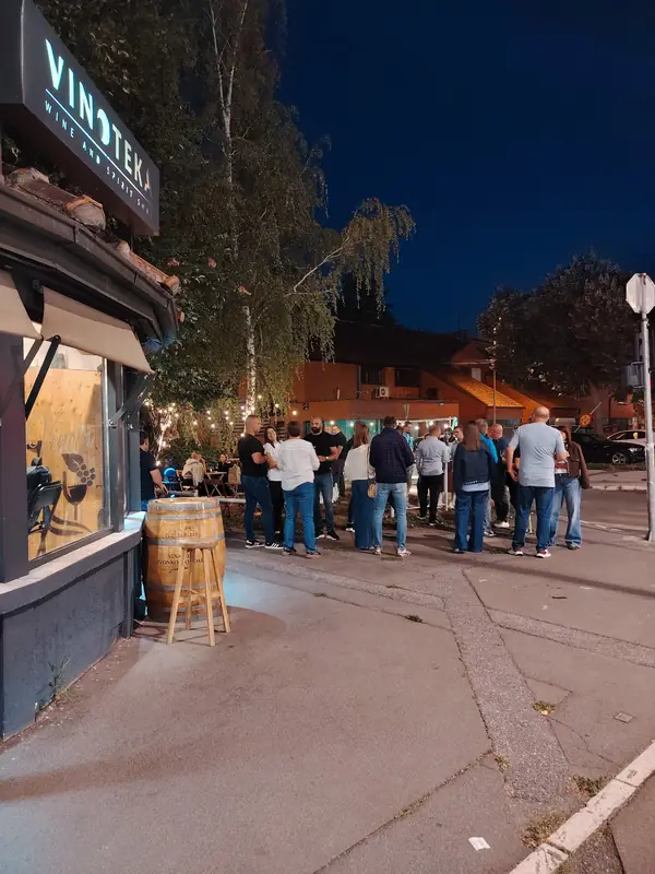 Ljudi se druže ispred vinoteke u predvečerje