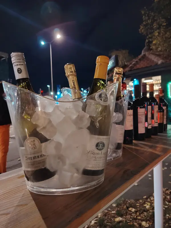 Boce penušavog i belog vina u posudi sa ledom, ispred vinoteke